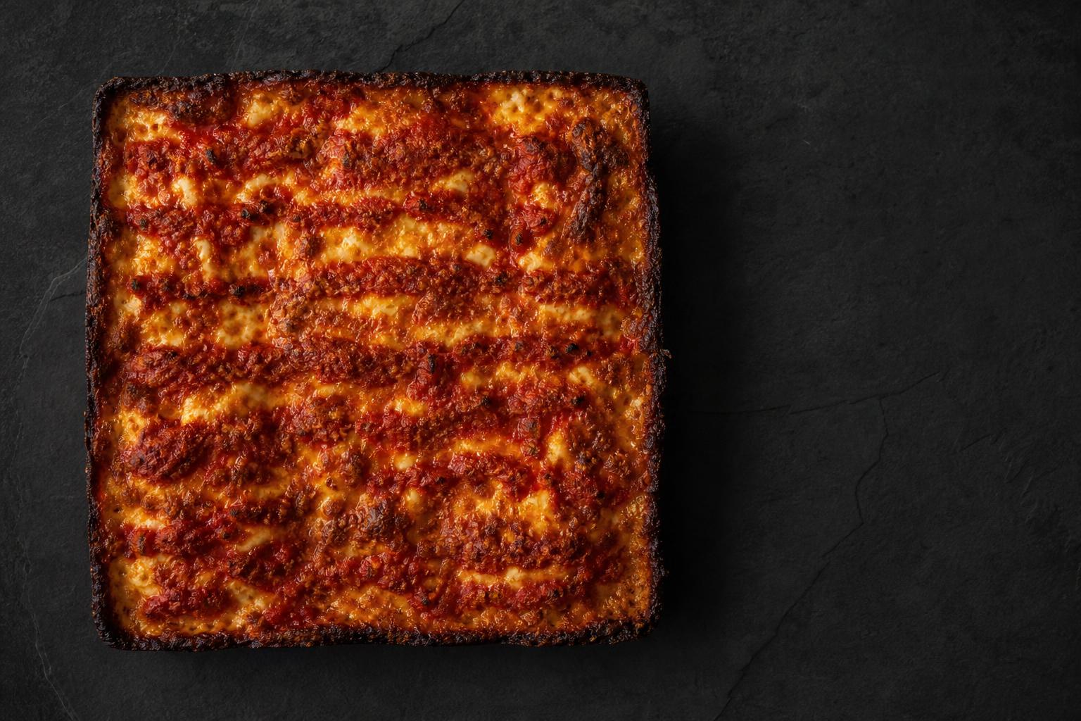 A square Old Forge tray pizza on dark slate